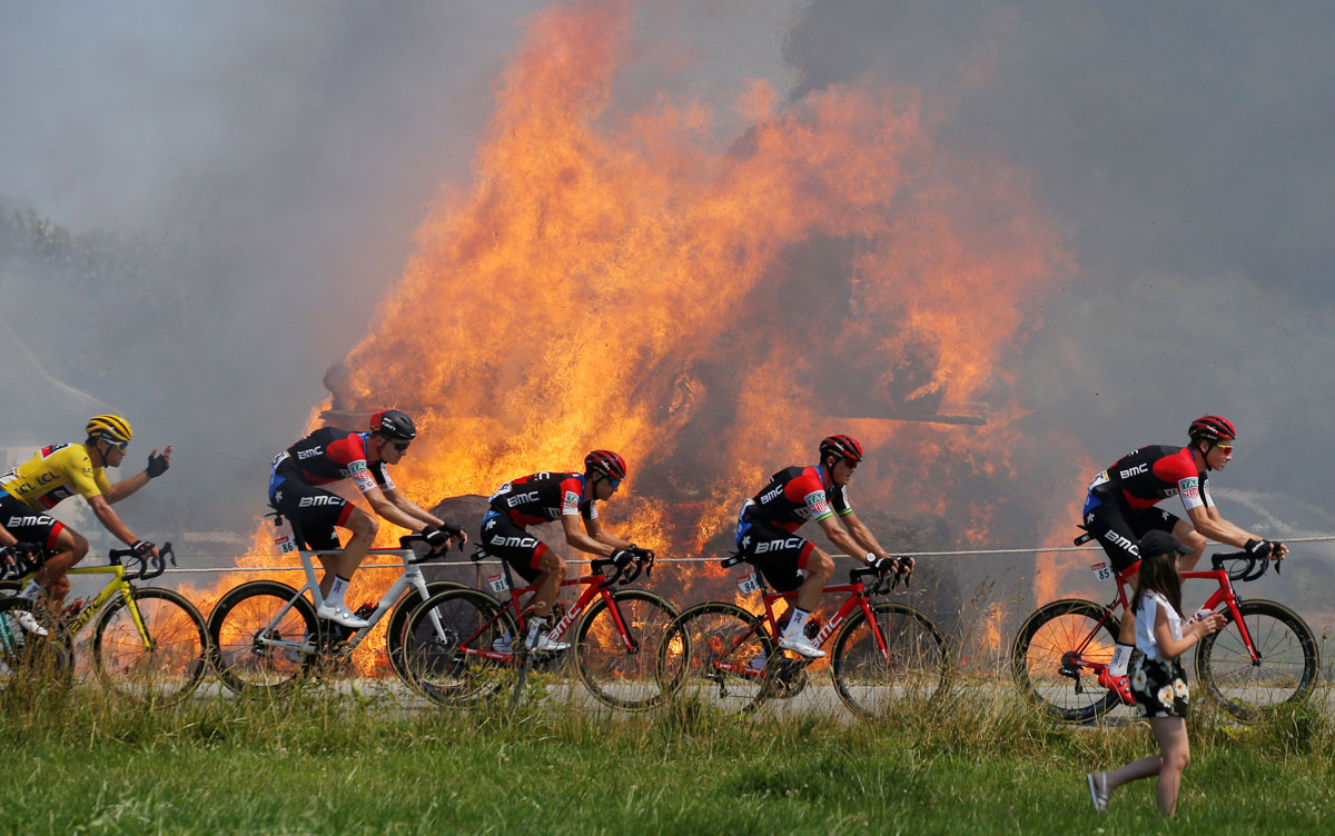 The peloton, with BMC Racing Team rider Greg Van Avermaet of Belgium in the overall leader's yellow jersey passes burning hay bales at the 181-km Stage 6 from Brest to Mur-de-Bretagne Guerleden on July 12