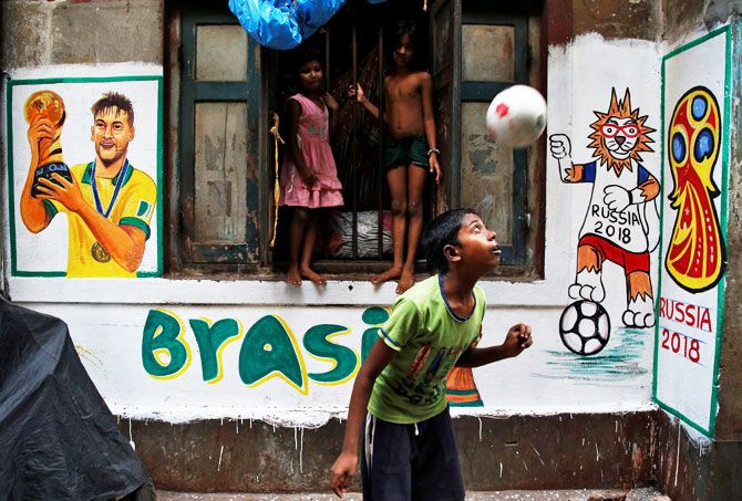 A boy plays in front an image of Brazil's Neymar painted on a wall in an alley at a slum in Kolkata on June 7