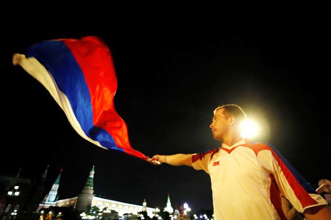 A Russian fan waves a national flag in Moscow as he celebrates the World Cup victory over Egypt on Wednesday
