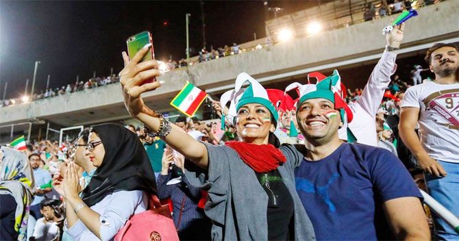Iranian women are seen with their male friends, enjoying the FIFA World Cup match between Portugal and Iran on a big screen at Tehran's Azadi Stadium
