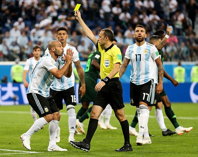 Referee Cuneyt Cakir shows Argentina's Javier Mascherano a yellow card during the Group D against Nigeria