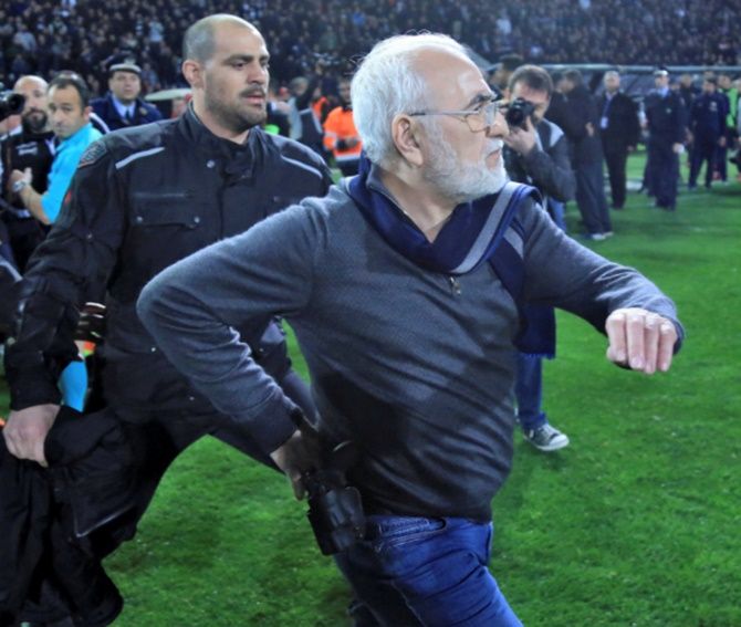 Russian-born Greek businessman and owner of PAOK Salonika, Ivan Savvides, centre, pictured with what appears to be a gun in a holster, enters the pitch after the referee annulled a goal of PAOK during their soccer match against AEK Athens on March 12
