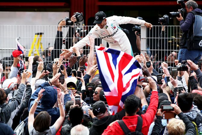 Mercedes GP's Lewis Hamilton celebrates with fans on the pit wall after winning the Spanish Formula One Grand Prix at Circuit de Catalunya in Montmelo, Spain, on Sunday