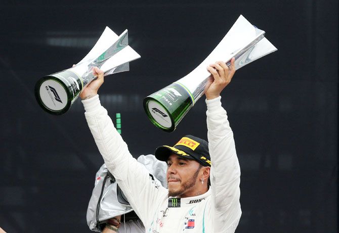 Mercedes' Lewis Hamilton celebrates with the constructors championship trophy and the race trophy after winning the Brazil F1 GP at Autodromo Jose Carlos Pace, in Interlagos, Sao Paulo on Sunday