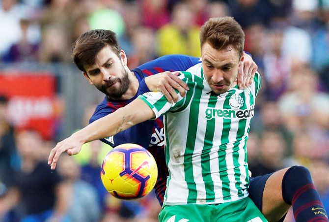 Real Betis' Loren Moron is challenged by with Barcelona's Gerard Pique