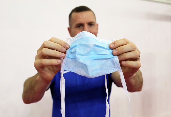 Swedish boxing coach Daniel Nash displays a medical face mask that was provided by a hotel staff on Monday