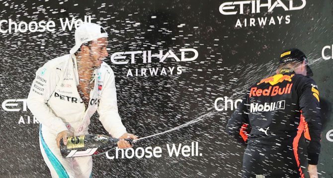 Mercedes' Lewis Hamilton celebrates winning the race on the podium with second place Red Bull's Max Verstappen