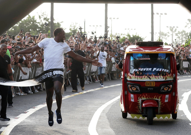 Usain Bolt runs against a moto-taxi as part of a sponsored event in Lima, Peru, on Tuesday, April 2