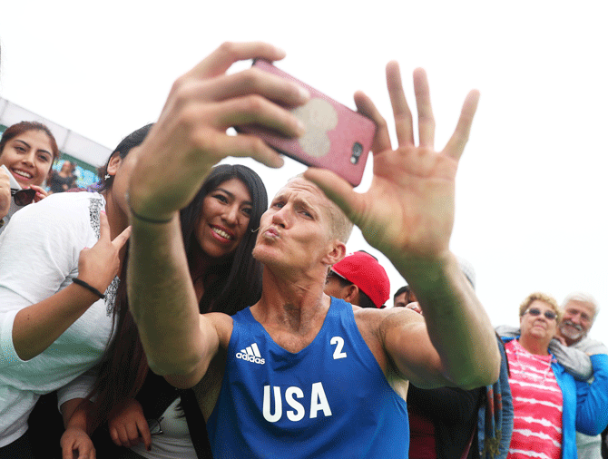Mark Burik of the US poses for a seflie with fans after the beach volleyball men's quarter-final against Canada on July 27