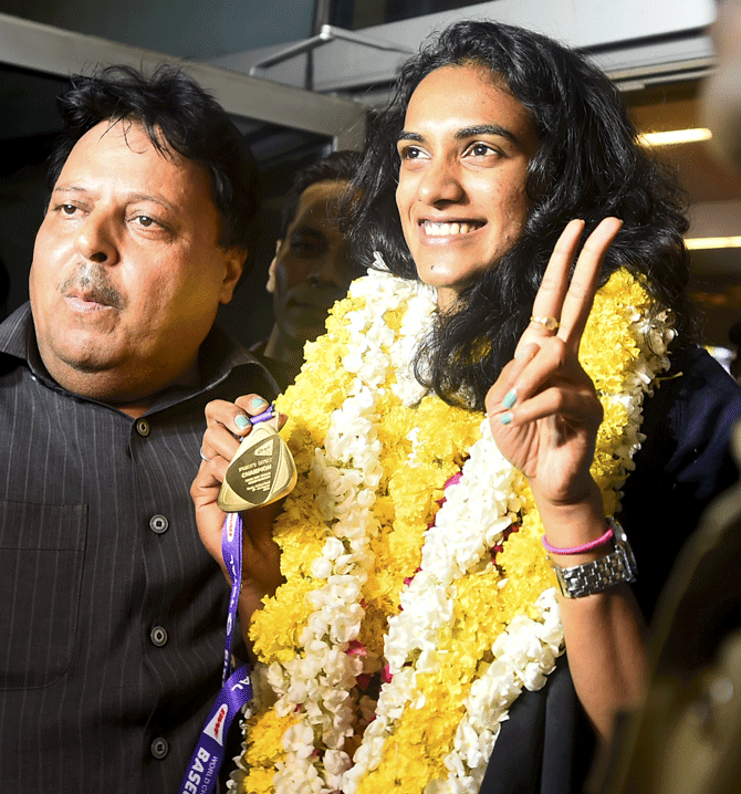 Newly crowned Badminton World Champion, India's ace badminton player PV Sindhu flashes victory sign on arrival from Basel, Switzerland, after winning the BWF World Championship, at the T-3 terminal of IGI Airport in New Delhi, late Monday