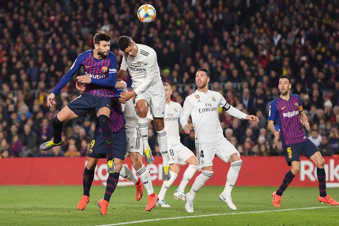 FC Barcelona's Gerard Pique and Real Madrid's with Raphael Varane vie for the ball in an aerial battle for possession