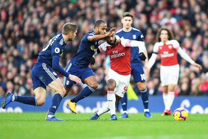 Arsenal's Alexandre Lacazette battles for possession with Fulham's Denis Odoi and Maxime Le Marchand during their match at Emirates Stadium