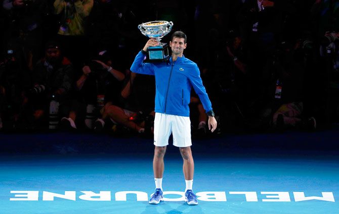 Novak Djokovic poses with the championship trophy after winning his match against Spain's Rafael Nadal on Sunday