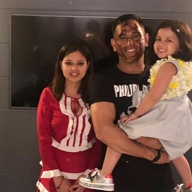Mahendra Singh Dhoni, his face smudged with cake, poses with his wife Sakshi and daughter Ziva during his birthday celebrations on Saturday