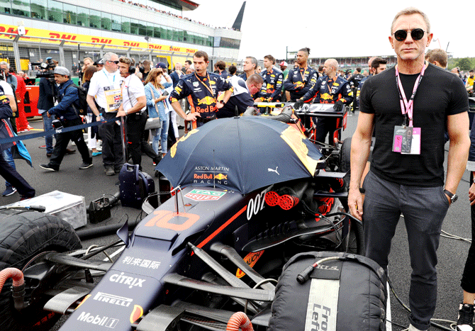 Actor Daniel Craig, who has essayed the role of James Bond in four films -- Casino Royale, Quantum of Solace, Skyfall and Spectre poses for a photo with French driver Pierre Gasly's Aston Martin Red Bull Racing car on the grid before the British F1 Grand Prix at Silverstone in Northampton, England, on Sunday