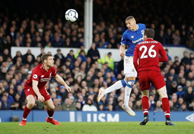 Everton's Richarlison heads the ball as Liverpool's James Milner and Andrew Robertson look on 