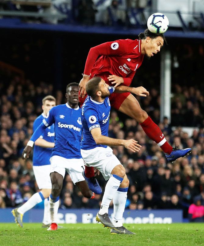 Liverpool's Virgil van Dijk wins the ball in an aerial challenge with Everton's Cenk Tosun