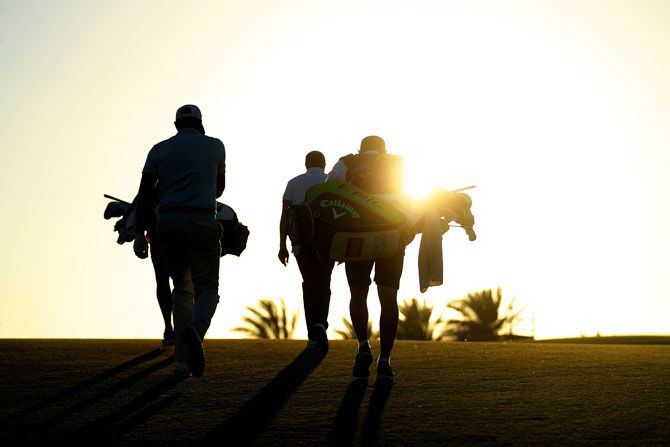 Players and caddies walk along the 7th hole as the sun sets during day two of the Commercial Bank Qatar Masters at Doha GC in Doha, Qatar, on Friday, March 8