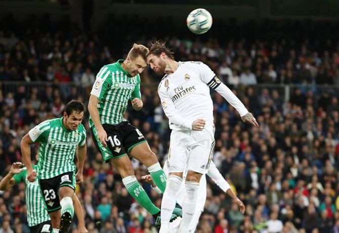 Real Madrid's Sergio Ramos and Real Betis's Loren battle for an aerial ball.