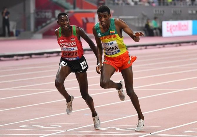 Kenya's Conseslus Kipruto and Ethiopia's Lamecha Girma cross the finish line together in the men's 3000 metres steeplechase final.