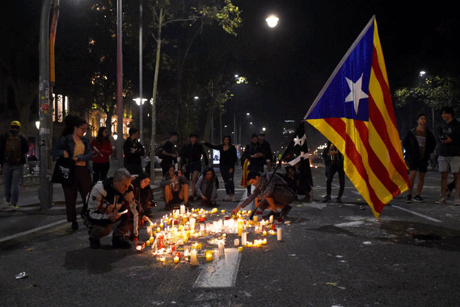 People hold a Catalan flag and light candles during a protest against the jailing of Catalan separatists in Mallorca Street near the Spanish Government Delegation in Barcelona, Spain on Tuesday. Spain's Supreme Court has sentenced nine Catalan separatist leaders to between nine and 13 years in prison over their role in the 2017 Catalan independence referendum