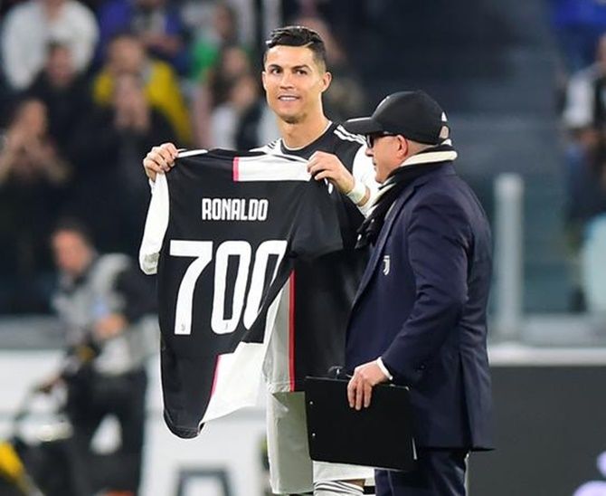 Juventus's Cristiano Ronaldo holds up a shirt to commemorate his 700 career goals before the match against Bologna.