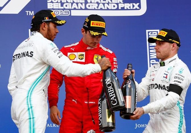 Ferrari's Charles Leclerc celebrates on the podium with second placed Lewis Hamilton and third placed Valtteri Bottas.