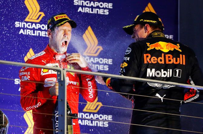Race winner Ferrari's Sebastian Vettel is sprayed in the face with sparkling wine by third placed Red Bull's Max Verstappen as they celebrate on the podium