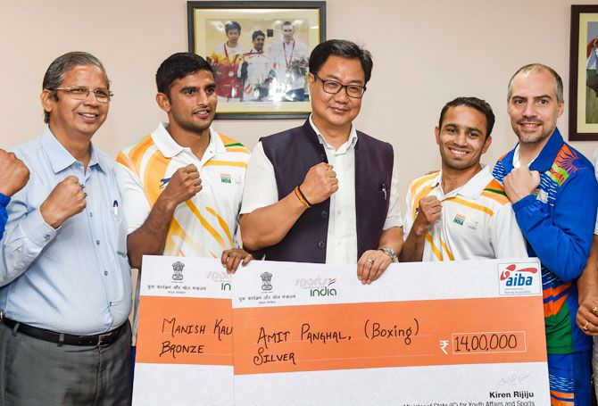 Union Sports Minister Kiren Rijiju presents cheques to boxers Amit Phogal and Manish Kaushik on Monday, for winning silver and bronze medals, respectively at the World Boxing Championship in Russia
