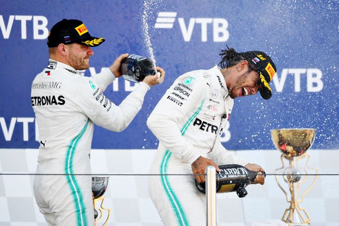 Lewis Hamilton is sprayed on with champagne as he celebrates on the podium with teammate and second-placed Valtteri Bottas of Finland