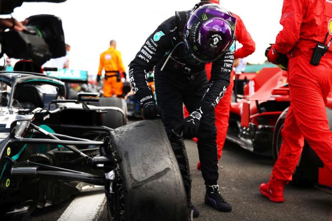 Race winner Lewis Hamilton inspects his punctured tyre in parc ferme