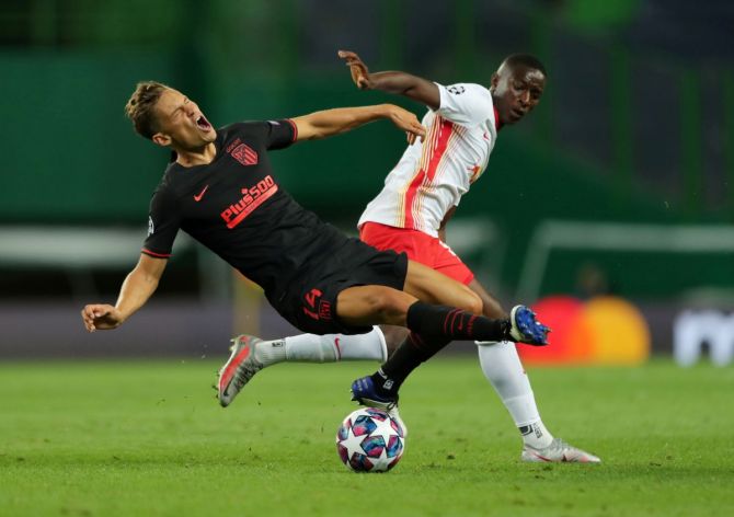 Atletico Madrid's Marcos Llorente slips while vying for possession with RB Leipzig's Amadou Haidara 