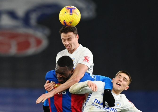 Leicester City's Jonny Evans heads the ball as he vies with a Crystal Palace player and a teammate during their English Premier League match at Selhurst Park, London on Monday.