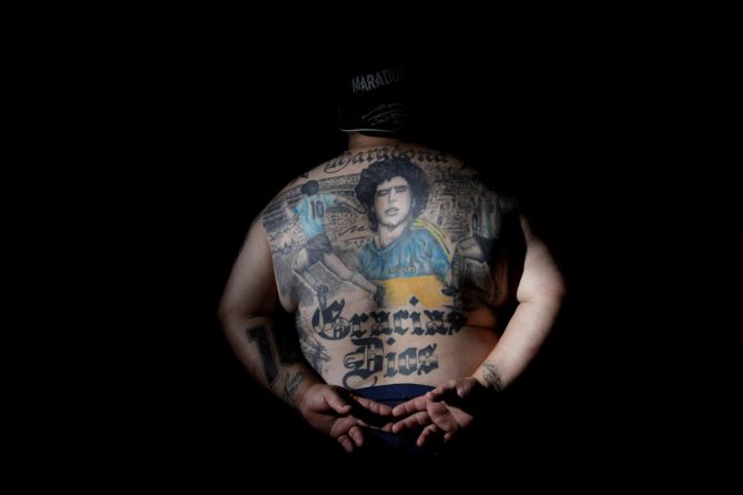 Guillermo Rodriguez, a devoted Diego Maradona fan who has images of Maradona tattooed on his back and who owns a pizza shop called "Siempre al 10" referring to Maradona's jersey's number, poses for a photograph at his pizza shop in Buenos Aires
