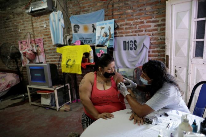 Cintia Veronica, a devoted Diego Maradona fan, gets an image of Maradona tattooed on her arm at her home in Buenos Aires