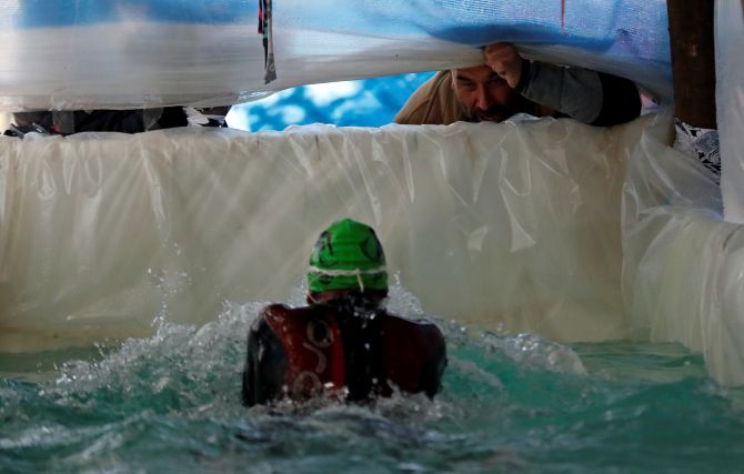 Edmundo Hernandez cheers on his son Sebastian Galleguillo during a training session in the swimming pool his family built for him