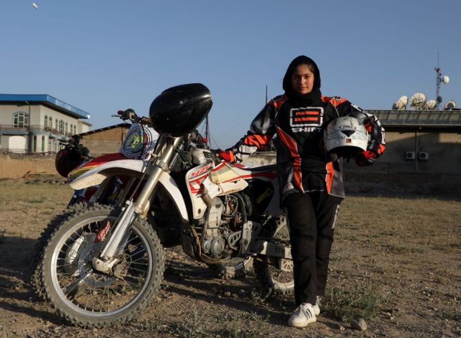 Wearing a white helmet and black and red motorbike suit, she trains with male riders on a barren lot surrounded by warehouses and private homes.