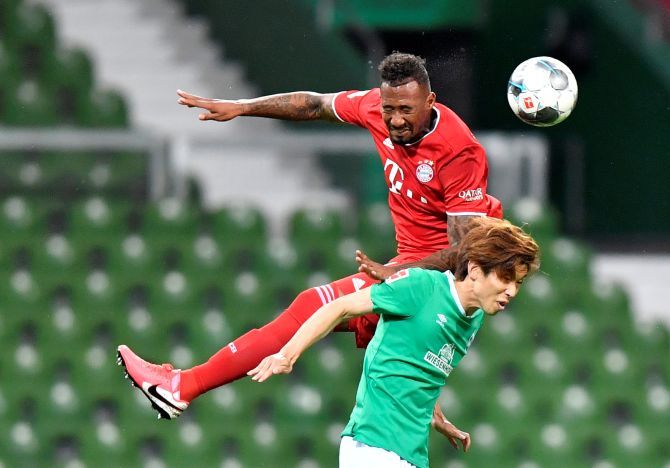 Bayern Munich's Jerome Boateng vies with Werder Bremen's Yuya Osako in an aerial battle for the ball