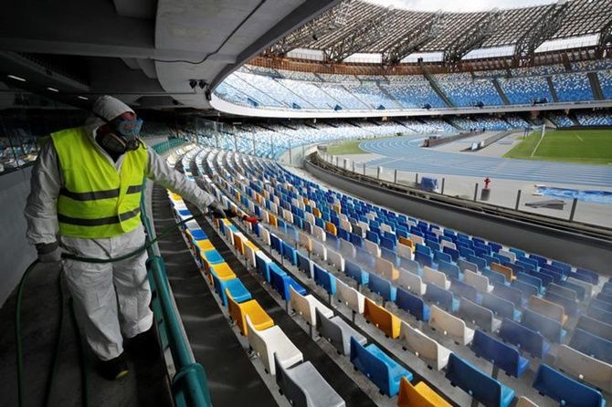 A cleaner wearing a protective suit sanitises seats at the San Paolo stadium ahead of the second leg of the Coppa Italia semi-final between Napoli and Inter Milan