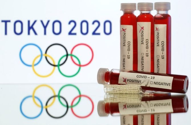 Fake blood in seen in test tubes labelled with coronavirus disease (COVID-19) in front of a displayed Tokyo 2020 Olympics logo in this illustration taken on March 19, 2020