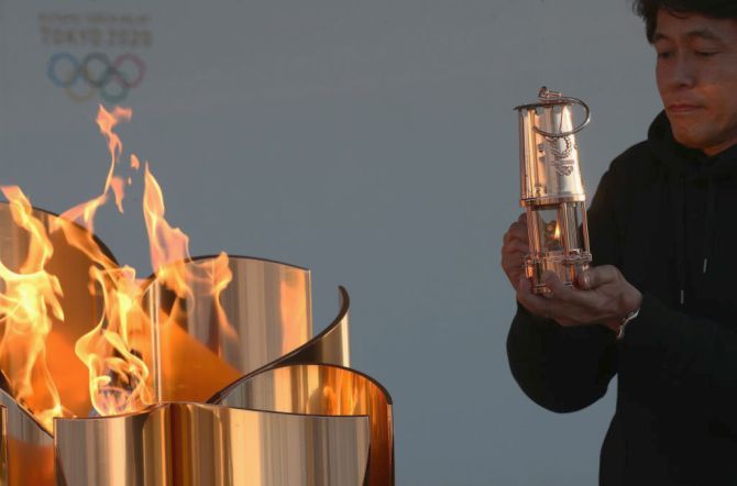 A staff preserves the Olympic flame to the lantern during the 'Flame of Recovery' special exhibition at Aquamarine Park in Iwaki, Fukushima, Japan, on Wednesday, March 25, a day after the postponement of the Tokyo 2020 Olympic and Paralympic Games was announced due to the coronavirus pandemic