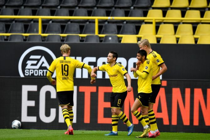 Borussia Dortmund's Raphael Guerreiro (centre) celebrates with teammate Julian Brandt (left) after scoring his side's second goal during their Bundesliga match at Signal Iduna Park on May 16, 2020 in Dortmund, Germany. The Bundesliga and Second Bundesliga is the first professional league to resume the season after the nationwide lockdown due to the ongoing Coronavirus (COVID-19) pandemic. All matches until the end of the season will be played behind closed doors.