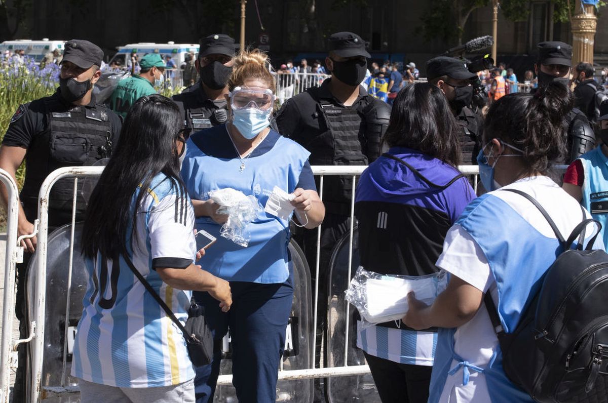 People offer masks as fans attend the funeral for Diego Maradaona at Casa Rosada