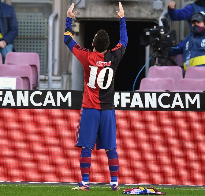Lionel Messi celebrates scoring Barcelona's fourth goal against Osasuna while wearing a Newell's Old Boys shirt with the number 10 on the back in memory of former footballer Diego Maradona