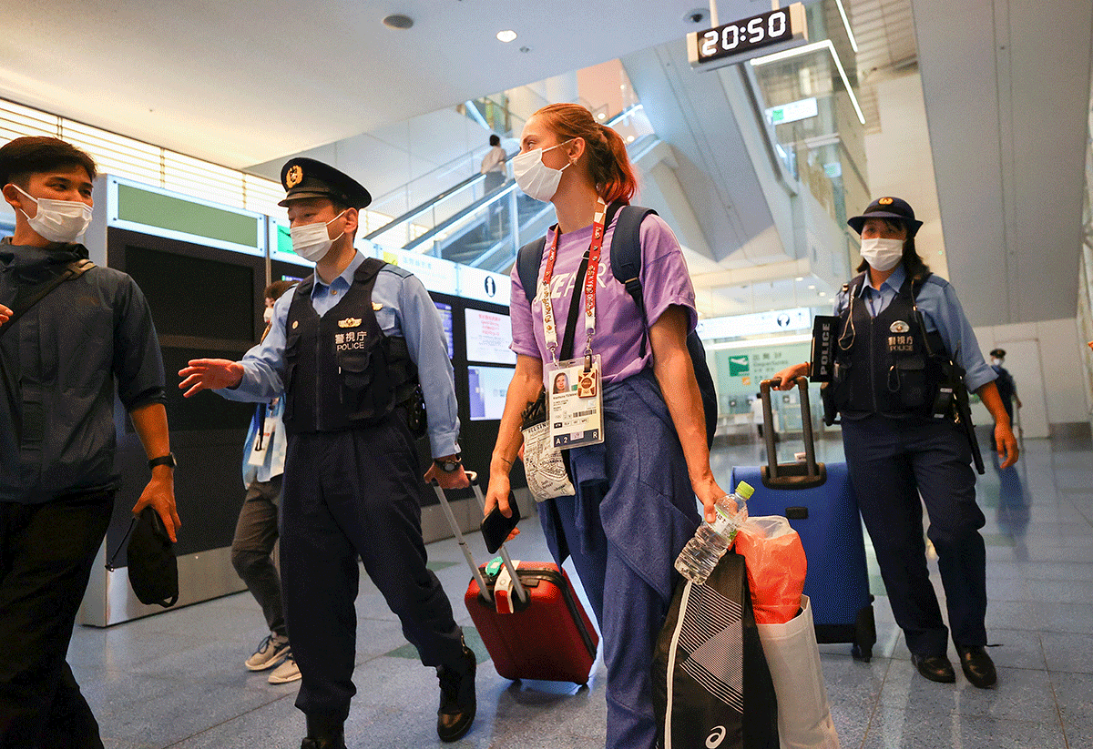 Belarusian athlete Krystsina Tsimanouskaya is escorted by police officers at Haneda international airport in Tokyo, on Sunday. Tsimanouskaya added that she had reached out to members of the Belarusian diaspora in Japan to retrieve her at the airport