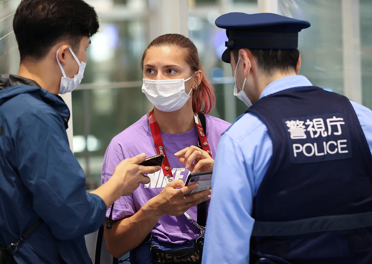 Belarusian athlete Krystsina Tsimanouskaya talks with a police officer at Haneda international airport in Tokyo, Japan, on Sunday