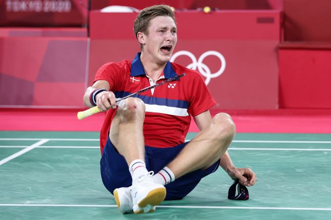 Denmark's Viktor Axelsen weeps in joy after defeating China's Chen Long in the Tokyo Olympics men's singles badminton final.