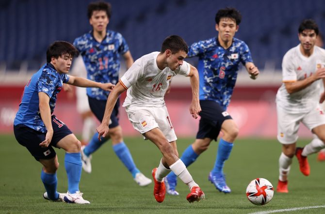 Spain's Pedri Gonzalez is challenged by a host of Japanese defenders as he shoots at goal. 