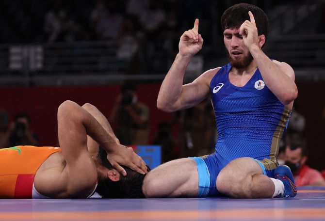 Zavur Uguev celebrates winning the gold medal, while a dejected Ravi Dahiya reacts after losing the bout.