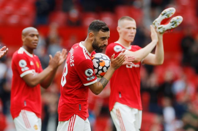Bruno Fernandes celebrates his hat-trick with the match ball as Manchester United's players walk back after the Premier League match against Leeds United, at Old Trafford, on Saturday.